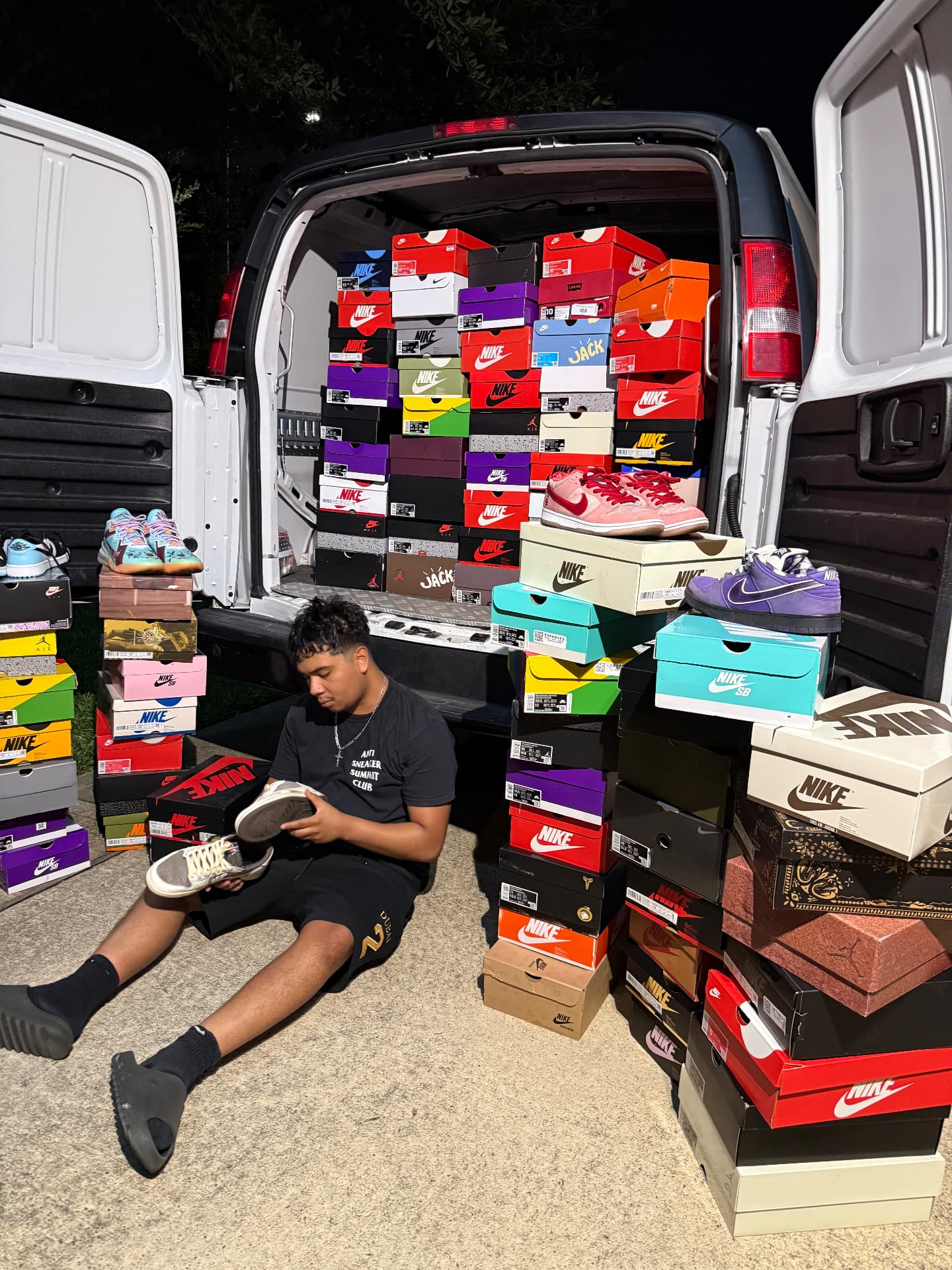 PB.Kickss buyer sorting a large sneaker collection loaded into a van